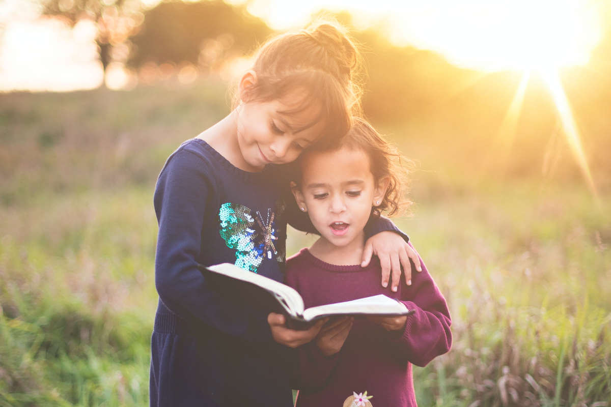 Dve devojčice čitaju knjigu u prirodi