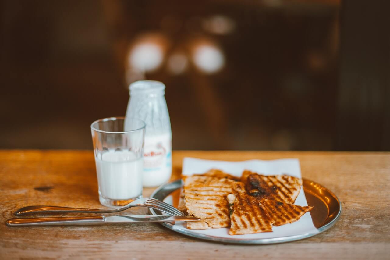 čaša mleka i doručak na drvenom stolu