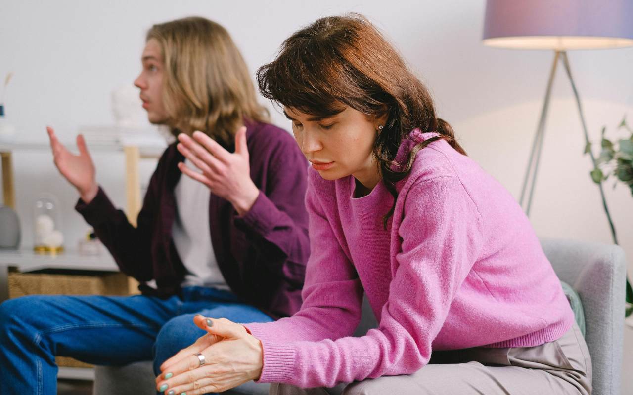 Muškarac i žena sede na kauču i razgovaraju.