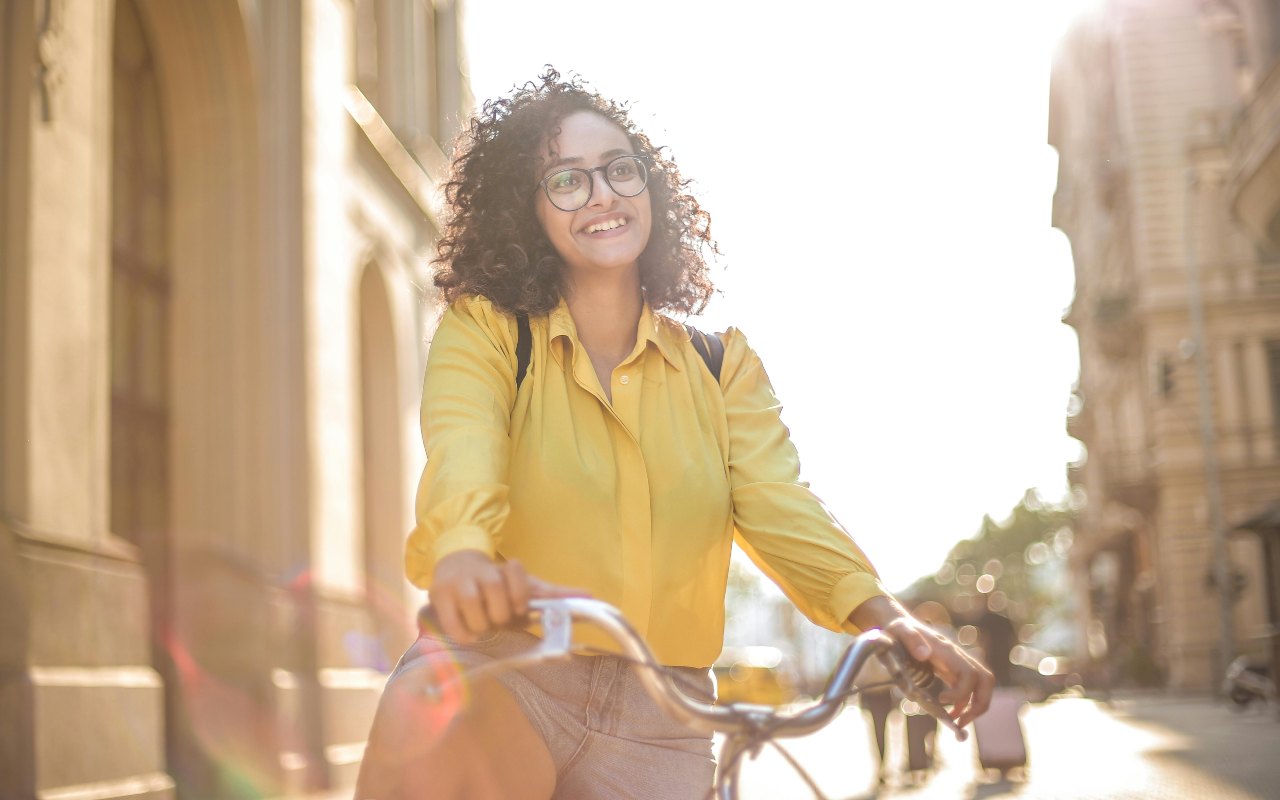 Žena sa naočarima vozi bicikl i pozira.
