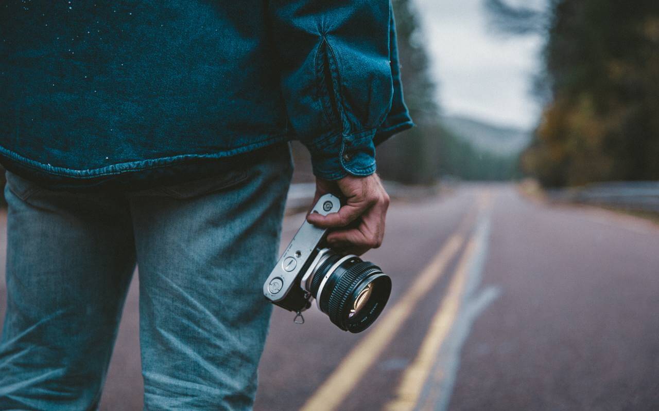 Čovek drži kameru i stoji na putu