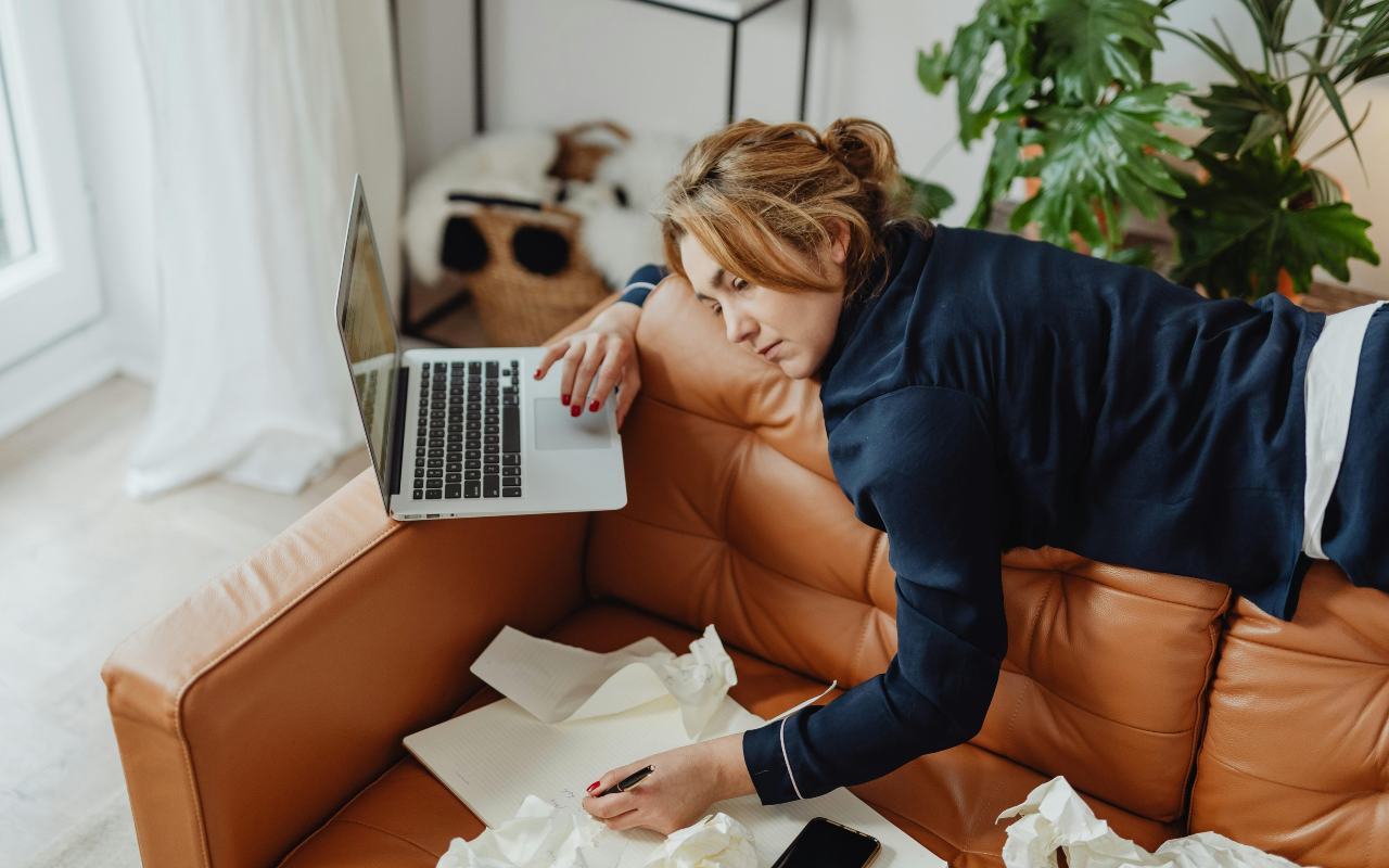Žena leži na kauču pored laptopa