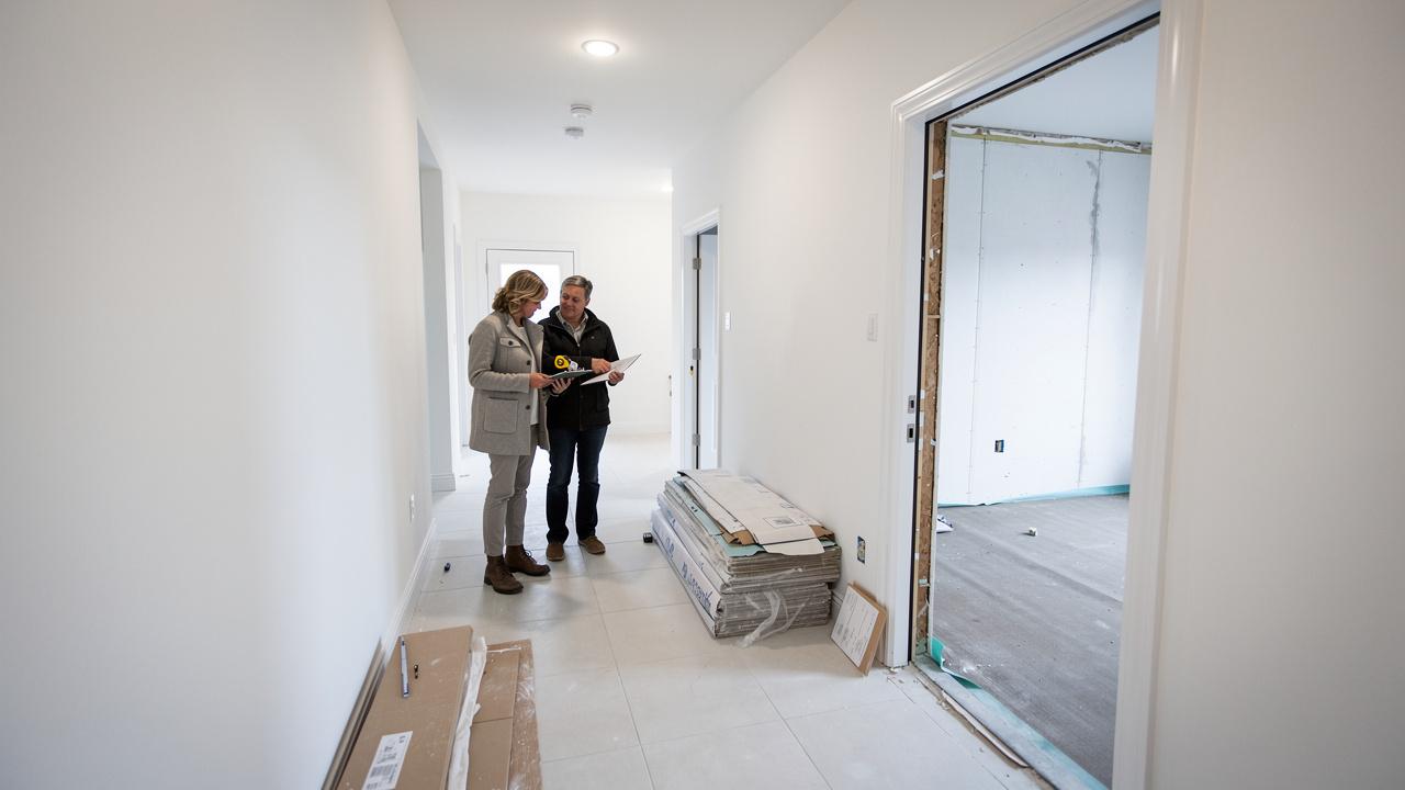 Par stoji u hodniku novogradnje i pregleda planove renoviranja